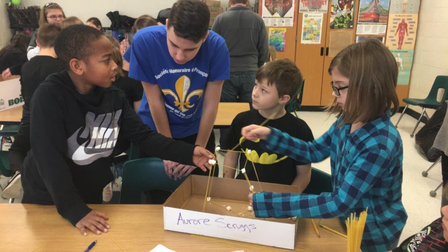 Junior Dawid Sikora helping Project Challenge kids strategize for their Eiffel Tower model.