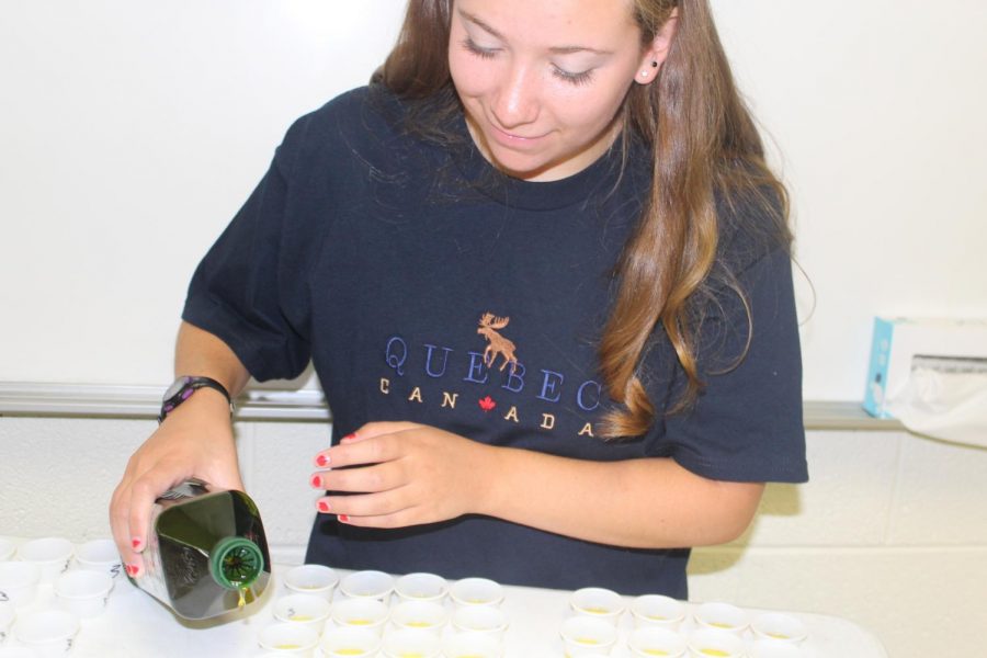 Senior Abigail Barnett helps guest speaker Aidan Pelish pour olive oil into tasting cups for the class to sample.